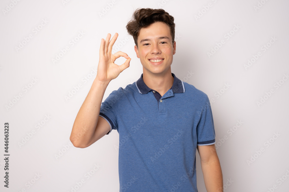 Happy young man in casual clothing with okay sign isolated over white background. Happy young man in casual clothing with okay sign isolated over white background.