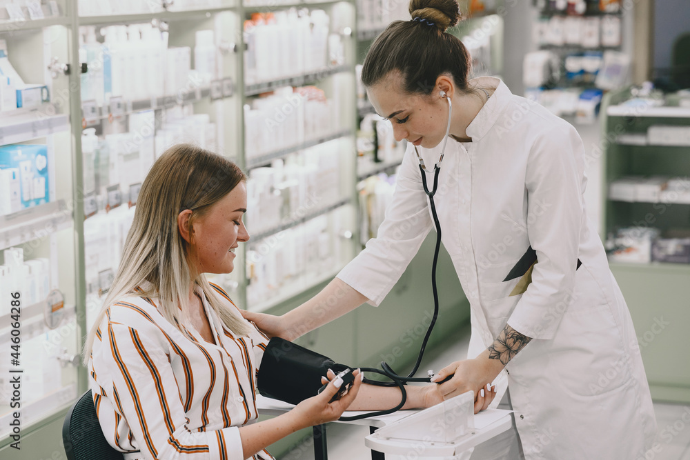 Fototapeta premium Trainee taking blood pressure of his customer in the pharmacy