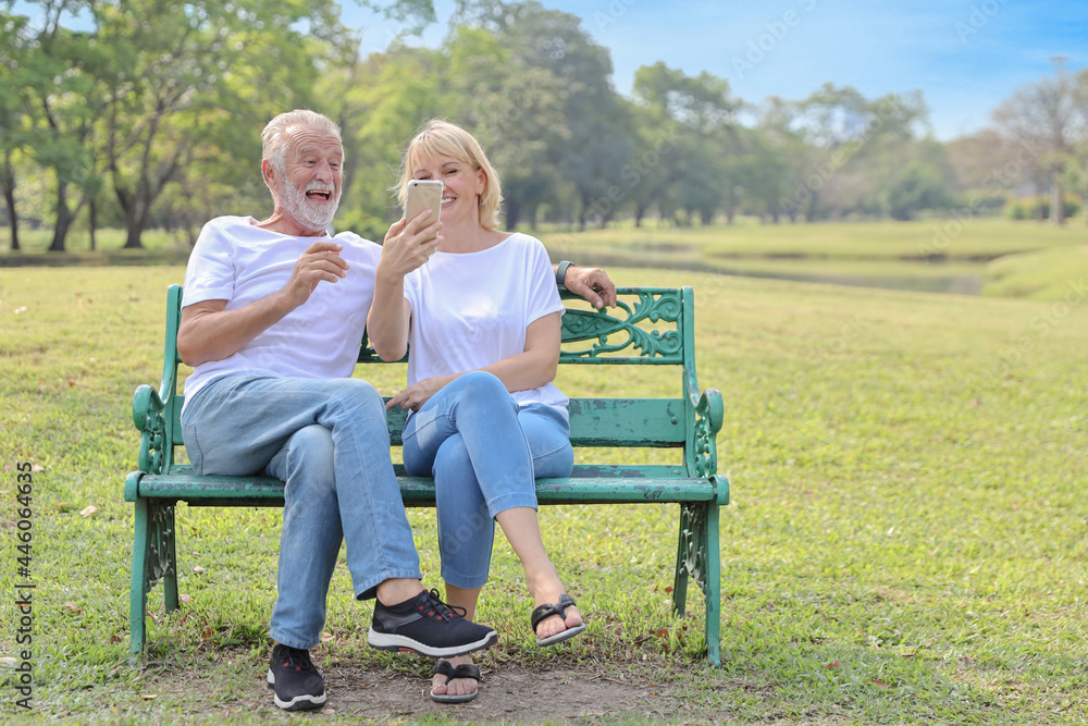 senior caucasian grandfather and grandmother sitting in park while using video call from smart phone to grandchildren with happy face and laughing senior caucasian grandfather and grandmother sitting in park while using video call from smart phone to grandchildren with happy face and laughing