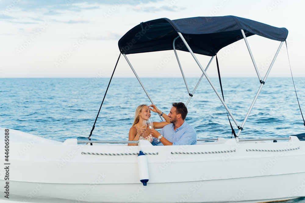 Obraz premium Happy young tourist couple strolling and enjoying a glass of cava on a boat.