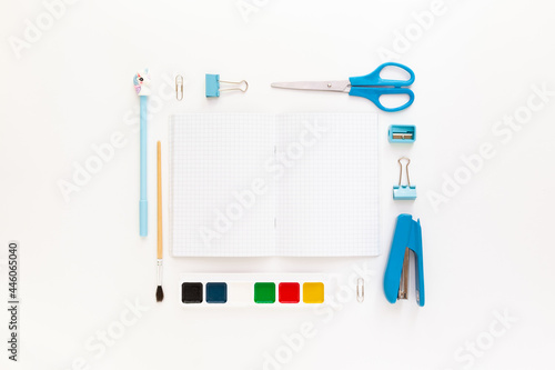 Top view of modern white blue office desktop with school supplies and stationery on table around empty space for text. Back to school concept flat lay with mockup