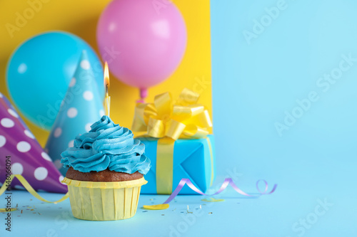 Delicious birthday cupcake with candle on color background, space for text