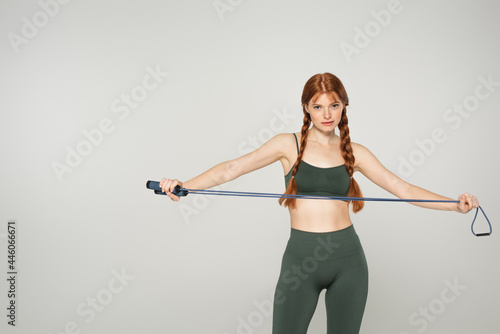 Sportswoman with freckles holding skipping rope isolated on grey © LIGHTFIELD STUDIOS