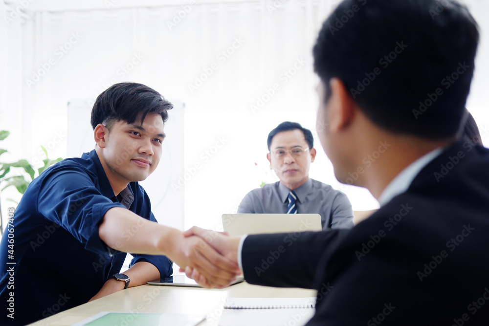 Smiling successful Asian businessmen and teamwork in black suit is shaking hand with partnership for a big project in meeting room at office. Business and marketing concept. Smiling successful Asian businessmen and teamwork in black suit is shaking hand with partnership for a big project in meeting room at office. Business and marketing concept.