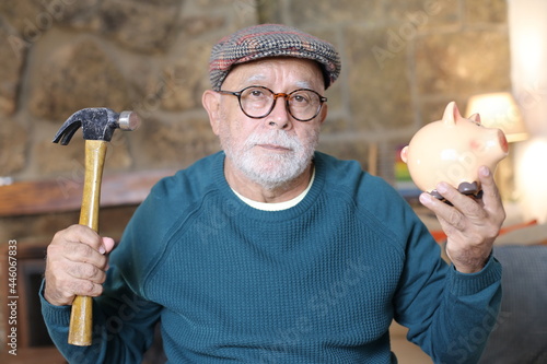 Obraz na płótnie Desperate senior man about to destroy piggy bank