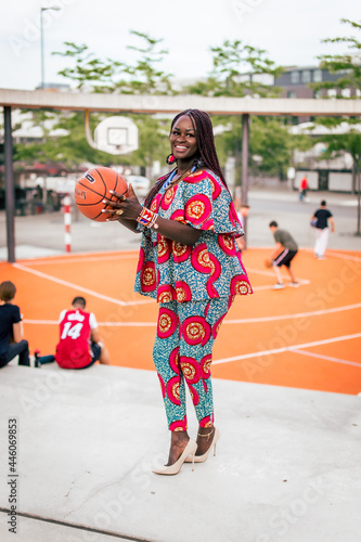 African woman holding at a basketball and smiling www.threethroneproductions.com