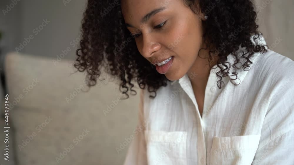 Happy young woman relaxing on cozy couch, using smartphone. Smiling millennial mixed race girl looking at cellphone screen, typing message for friend in social network, shopping online, web surfing. Happy young woman relaxing on cozy couch, using smartphone. Smiling millennial mixed race girl looking at cellphone screen, typing message for friend in social network, shopping online, web surfing.
