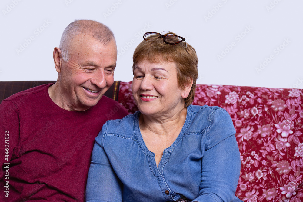 Relaxed contented smiling old couple sitting together on the couch with glasses for reading on the wife head. Relaxed contented smiling old couple sitting together on the couch with glasses for reading on the wife head.
