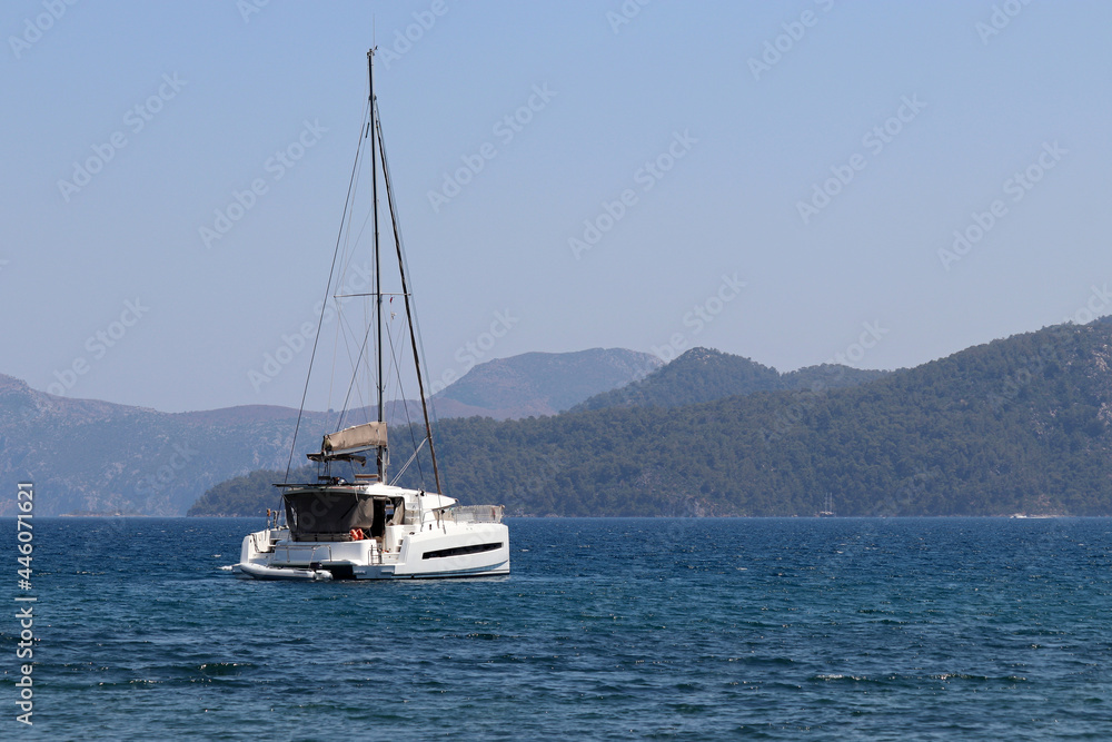 One-masted sailing yacht in Aegean sea. White sailboat on misty mountains background One-masted sailing yacht in Aegean sea. White sailboat on misty mountains background