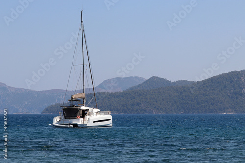 One-masted sailing yacht in Aegean sea. White sailboat on misty mountains background