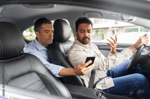 transportation, vehicle and technology concept - male passenger showing smartphone to car driver