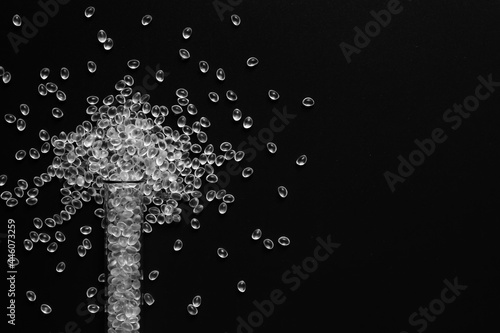 white granules of rubber and polypropylene on a black background in a chemical test tube. Plastics and polymers industry.