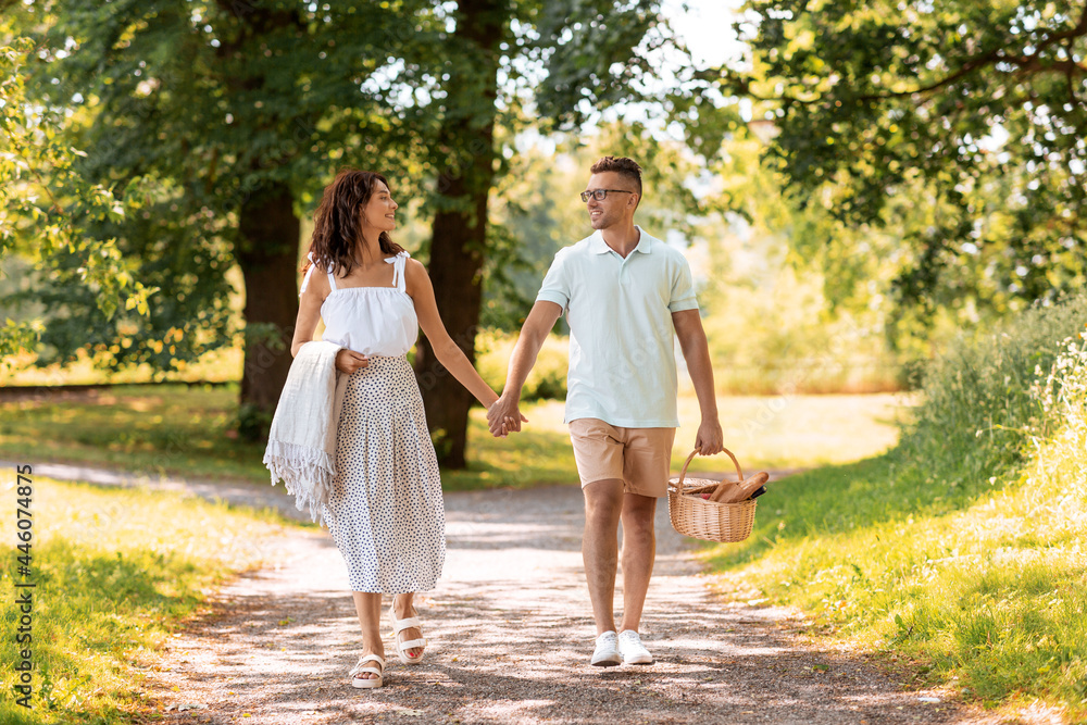 leisure, vacation and people concept - happy couple with picnic basket and blanket walking at summer park leisure, vacation and people concept - happy couple with picnic basket and blanket walking at summer park