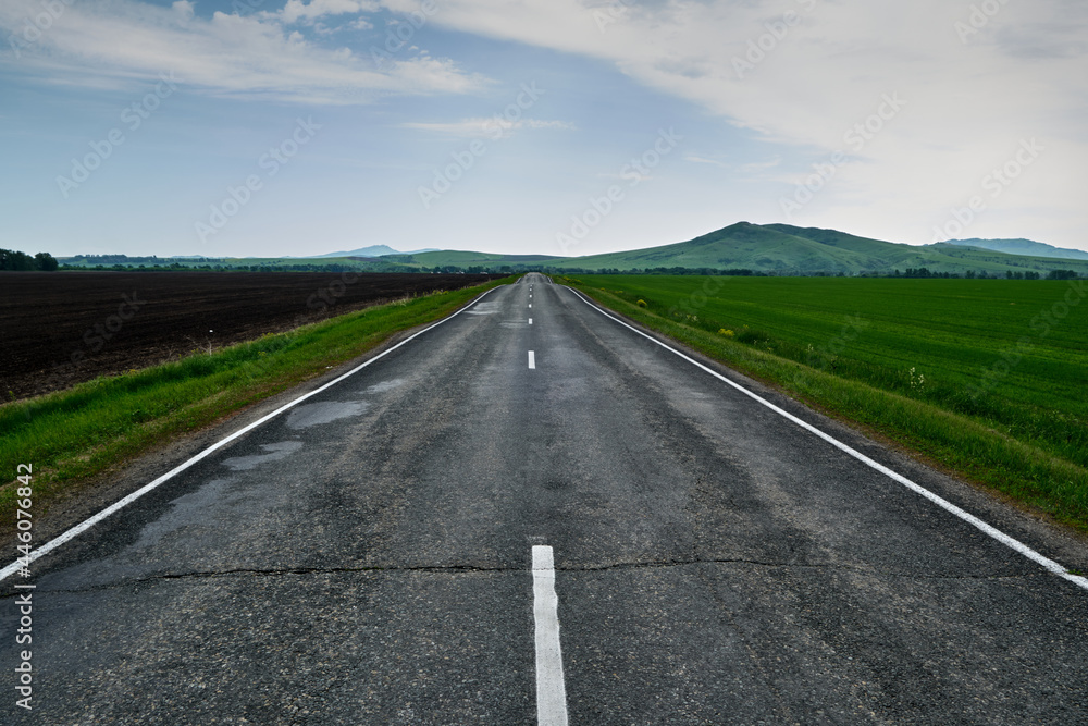 Fototapeta premium The road leading into the distance to the mountains after the rain.