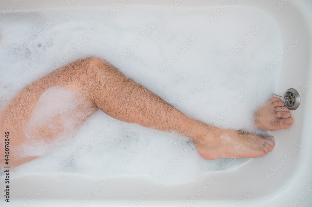Funny picture of a man taking a relaxing bath. Close-up of male feet in a bubble bath. Top view Funny picture of a man taking a relaxing bath. Close-up of male feet in a bubble bath. Top view