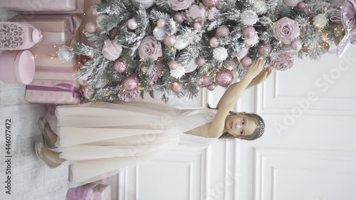 child decorating Christmas tree in studio