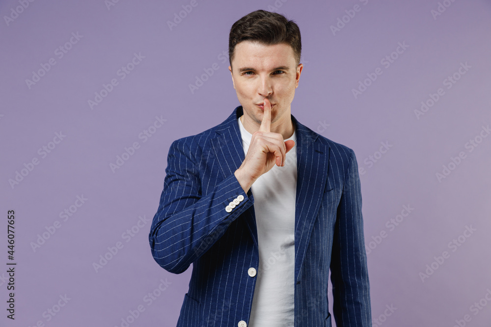Secret young employee business man corporate lawyer 20s wears formal blue suit white t-shirt work in office say hush be quiet with finger on lips isolated on pastel purple background studio portrait. Secret young employee business man corporate lawyer 20s wears formal blue suit white t-shirt work in office say hush be quiet with finger on lips isolated on pastel purple background studio portrait.