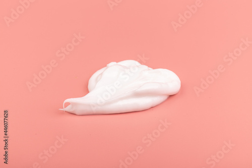 White cosmetic cream smear isolated on pink background. Skincare product creamy texture.