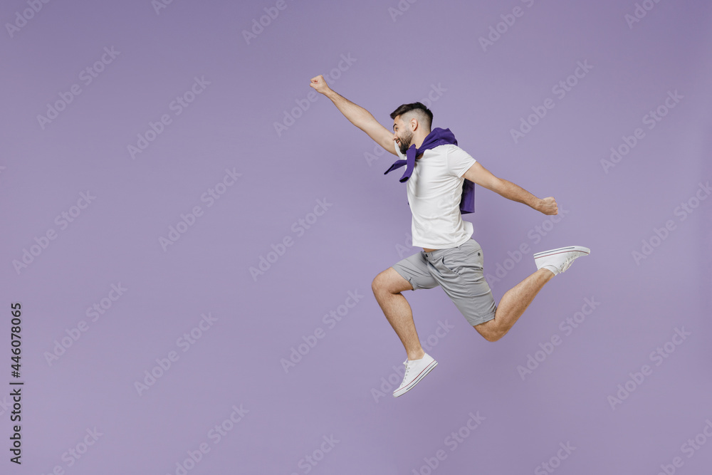 Full size body length side view young brunet man 20s wear white t-shirt purple shirt jumpdoing superman gesture isolated on pastel violet background studio portrait. People emotions lifestyle concept.