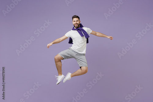 Full size body length fun young brunet man 20 wear white t-shirt purple shirt jump do clapping gesture with legs isolated on pastel violet background studio portrait. People emotion lifestyle concept
