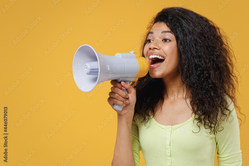 Cheery beautiful african american young brunette woman 20s wears green shirt hold scream in megaphone announces discounts sale Hurry up look aside away isolated on yellow background studio portrait Cheery beautiful african american young brunette woman 20s wears green shirt hold scream in megaphone announces discounts sale Hurry up look aside away isolated on yellow background studio portrait