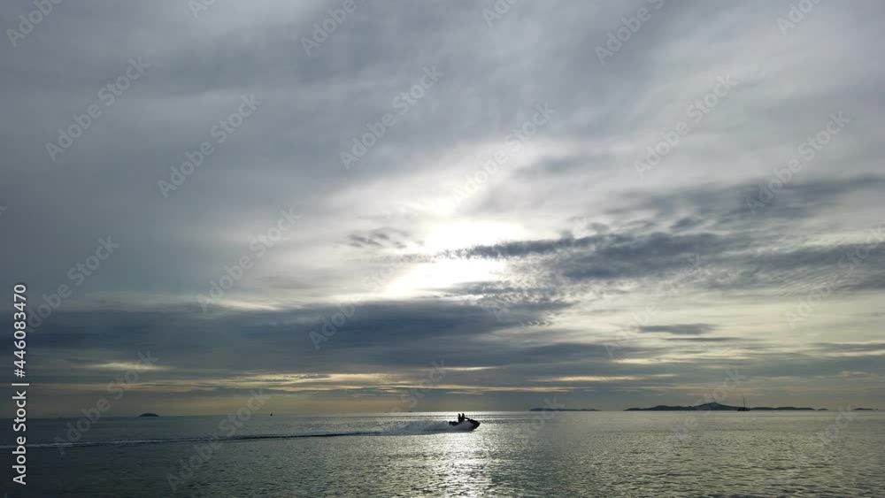 People riding Jet Ski and motor glider along coastline during sunset at the sea. People riding Jet Ski and motor glider along coastline during sunset at the sea.