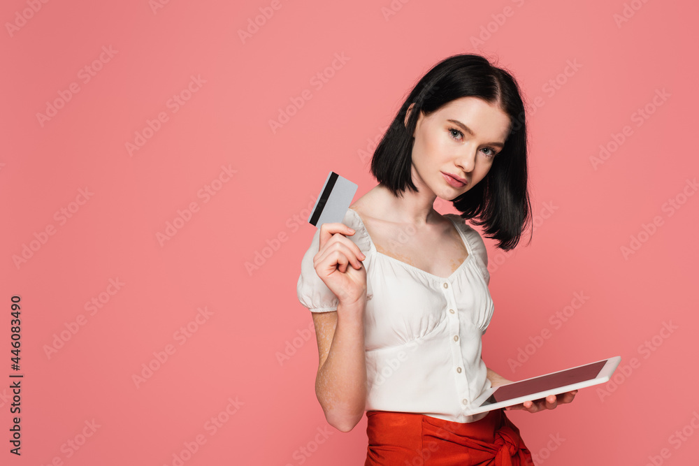 Woman with vitiligo holding digital tablet and credit card isolated on pink Woman with vitiligo holding digital tablet and credit card isolated on pink