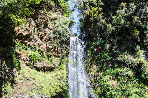 Una caída de agua dulce entre grandes montañas de rocas y arboles de hojas verdes photo