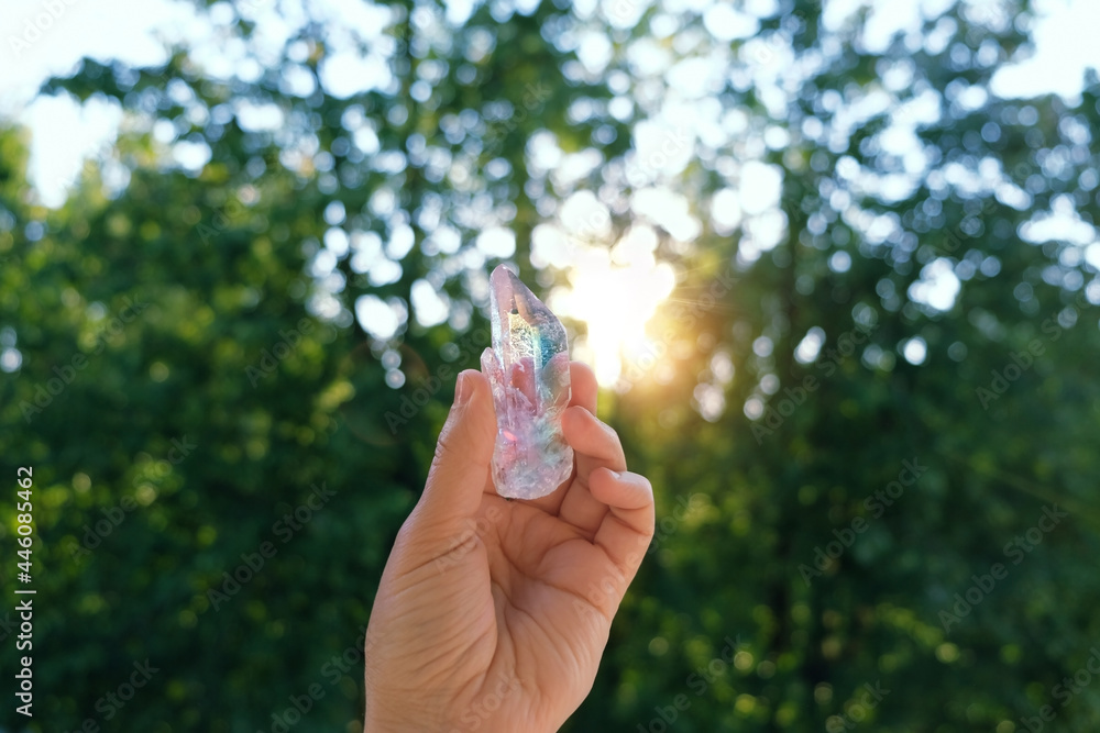 beautiful aura quartz crystal in hand, sunny natural forest background. Esoteric spiritual practice. Mysticism, divination, modern wicca occultism concept. Chakra Relaxation, Wiccan Witchcraft ritual