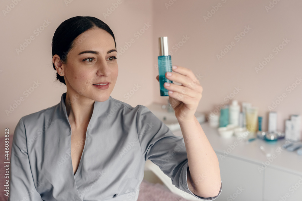 Professional cosmetologist in beauty salon showing cream for skincare treatment Professional cosmetologist in beauty salon showing cream for skincare treatment