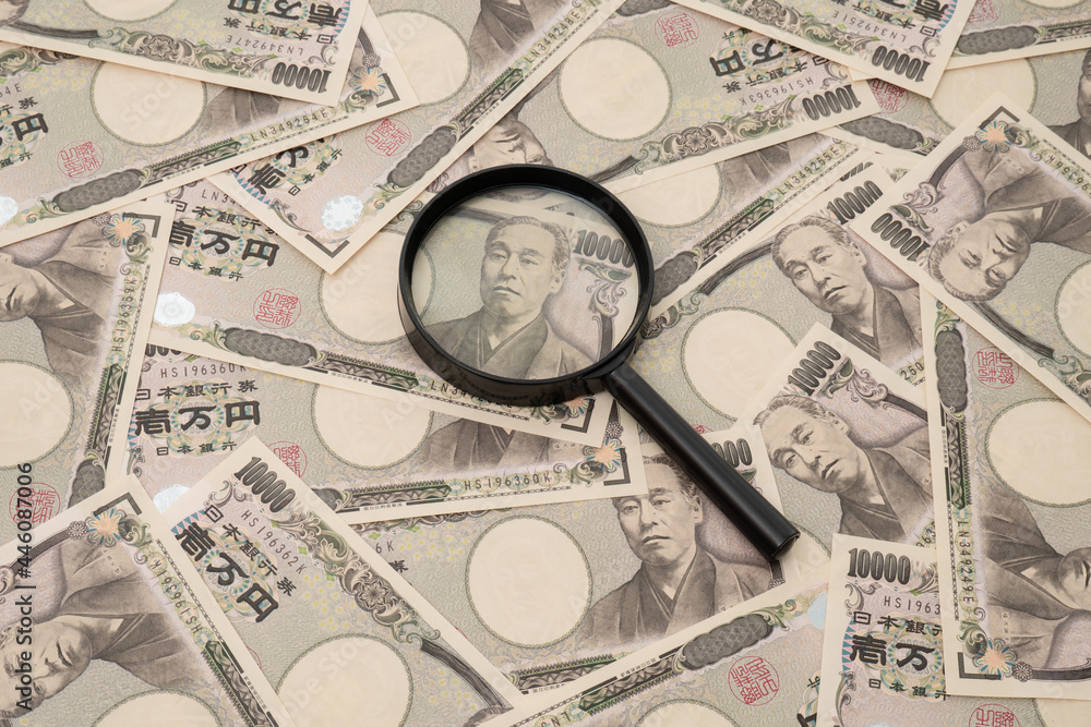 Many Japanese 10,000 yen bills and magnifying glass Many Japanese 10,000 yen bills and magnifying glass