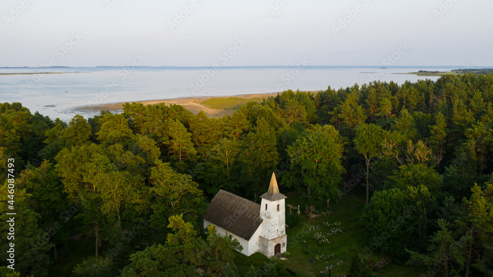 Aerial view to the historic small chapel with the thatched roof and wooden top of the bell tower on the coastal cemetery in Kassari, Hiiumaa island, Estonia