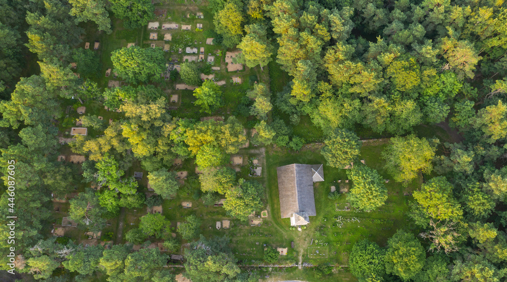 Aerial view to the historic small chapel with the thatched roof and wooden top of the bell tower on the coastal cemetery in Kassari, Hiiumaa island, Estonia