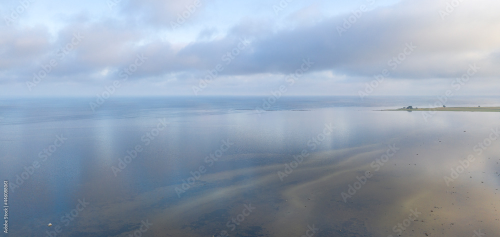 Aerial view to the coastal seascape with the low water sandbars and sunrise colored clouds reflecting from calm seawater in Luitemaa NR, Estonia