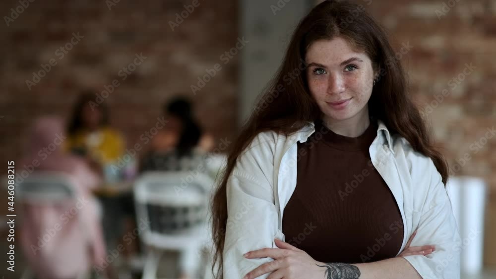 A young businesswomen is posing to the camera standing in a confident pose in the office A young businesswomen is posing to the camera standing in a confident pose in the office