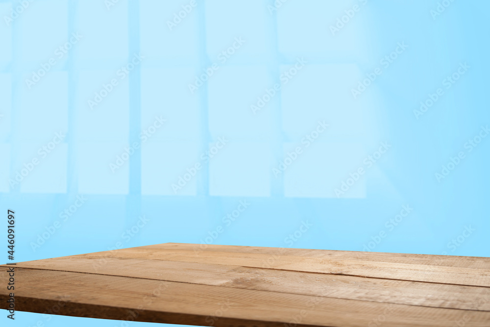 Naklejka premium Empty table top made of natural wood, light rays from the window on the background of the wall. For product demonstration and installation