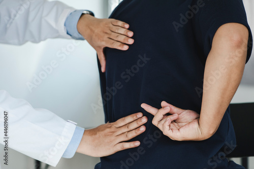 Closeup of a male Doctor or physiotherapist is doing stretching for a patient in the clinic for examining treating injured of back and Doing the Rehabilitation therapy pain