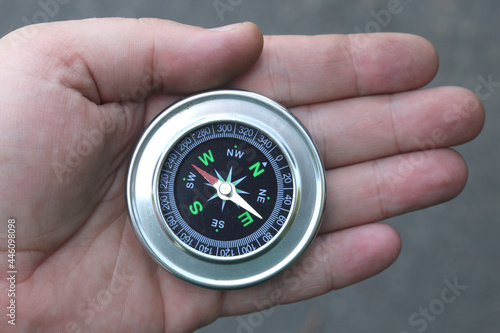 Old classic navigation compass in hand on natural background as symbol of tourism with compass, travel with compass and outdoor activities with compass