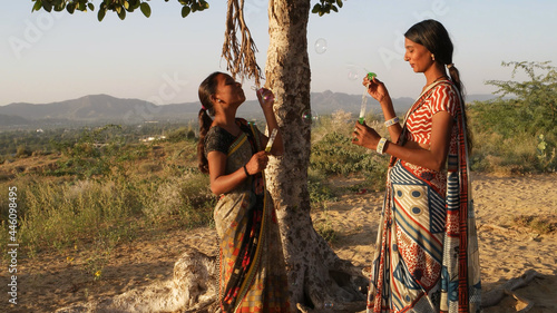 Two young Indian females making soap balls in the countryside under a clear sky photo