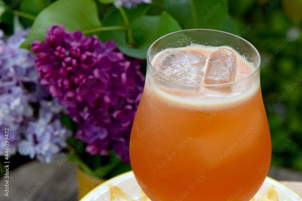 Scotch based cocktail with ice and lilac flower background Scotch based cocktail with ice and lilac flower background