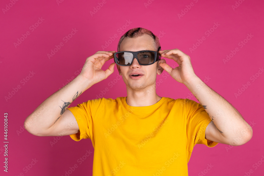 European handsome young man in yellow t shirt on pink background with 3 d cinema glasses European handsome young man in yellow t shirt on pink background with 3 d cinema glasses