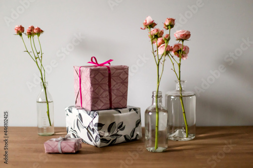 Pink roses and gifts on a wooden table