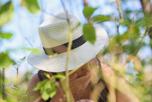 Tam, gdzie rosną poziomki. Dziewczyna w kapeluszu zajada leśne poziomki, w słoneczny letni dzień..