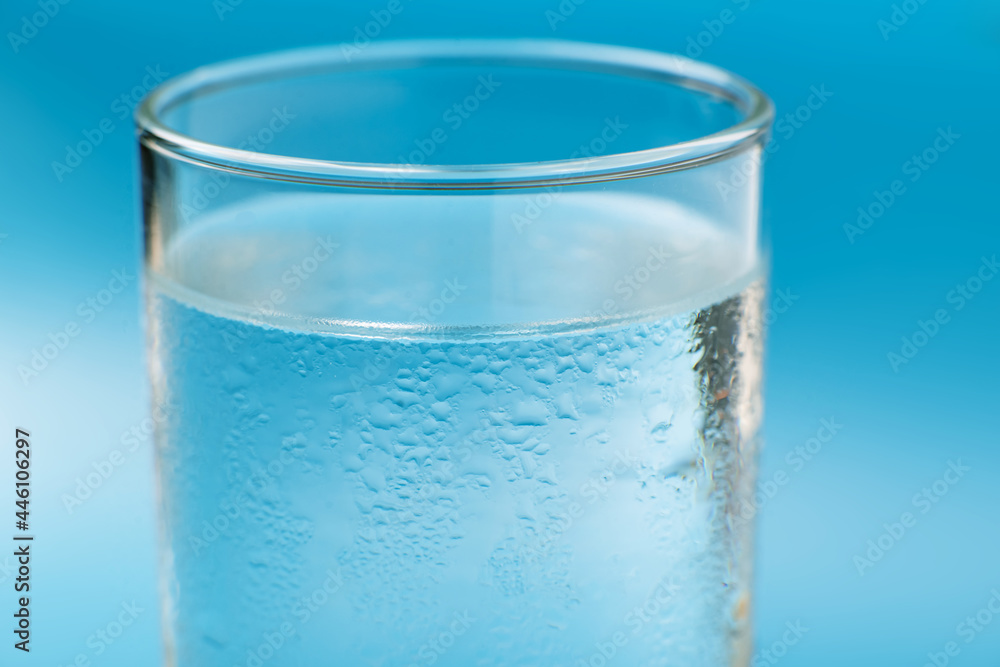 Glass of pure cold water on a blue background close-up wet. Glass of pure cold water on a blue background close-up wet.
