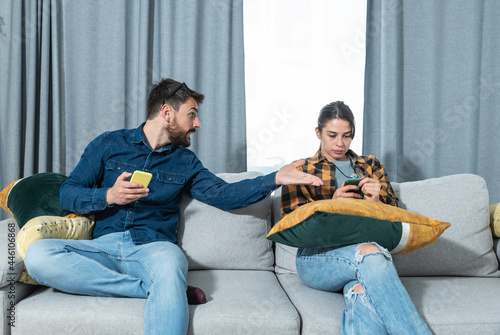 Young couple at home have a problem and argue due to jealousy caused by chatting and flirting via social media networks on smart phones, relationship difficulties problems and distrust