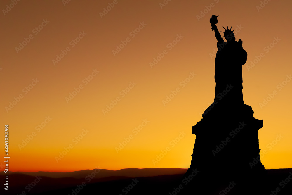Silhouette of the Statue of Liberty with a sunset golden and yellow background 