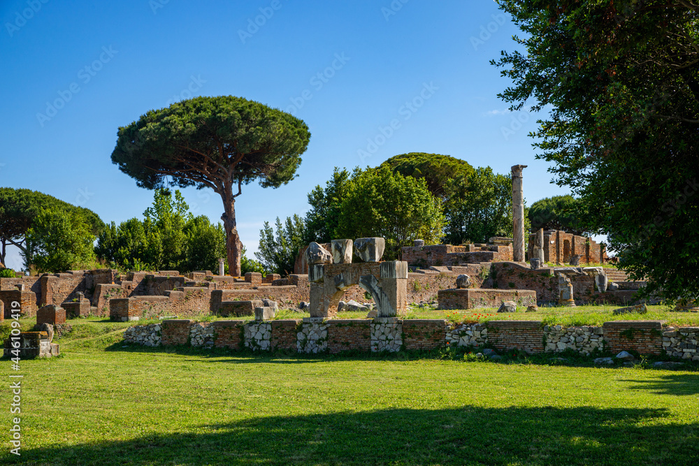 Ostia Antica site Rome, ruins of marble columns with brick buildings from the imperial era in Ostia Antica archaeological park in summer with blue sky. Rome Italy, Europe.