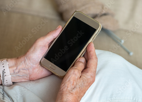Hands of an senior woman holding blank screen smartphone.