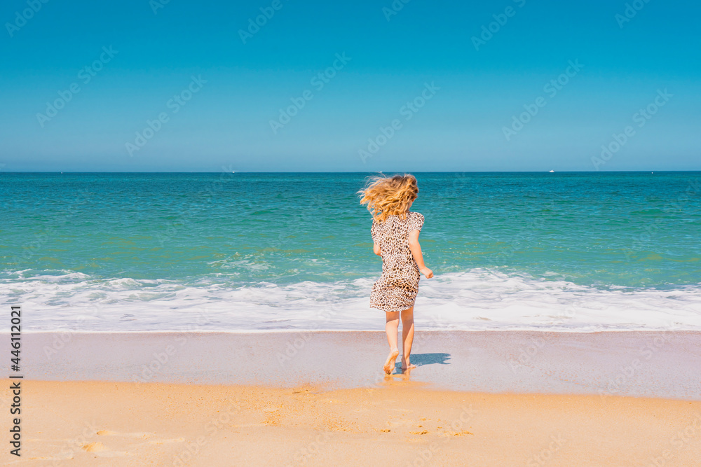 Young beautiful girl in beige dress running on the the sandy beach near the waves. High quality photo Young beautiful girl in beige dress running on the the sandy beach near the waves. High quality photo
