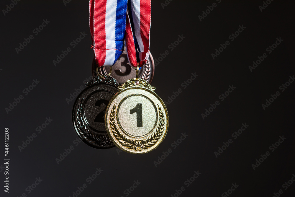 Three gold, silver and bronze medals hanging on a dark background. Sports and victory concept. Three gold, silver and bronze medals hanging on a dark background. Sports and victory concept.